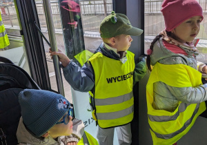 Dzieci jadą autobusem lotniskowym po terenie portu lotniczego.