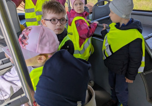 Dzieci jadą autobusem lotniskowym po terenie portu lotniczego.