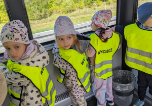 Dzieci jadą autobusem lotniskowym po terenie portu lotniczego.