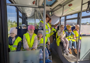 Dzieci jadą autobusem lotniskowym po terenie portu lotniczego.