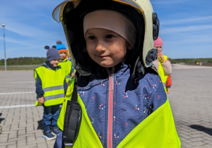 Dziecko przymierza kask strażacki.