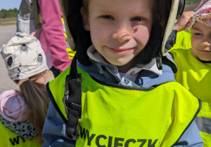 Dziecko przymierza kask strażacki.