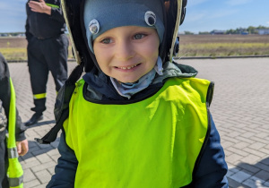 Dziecko przymierza kask strażacki.