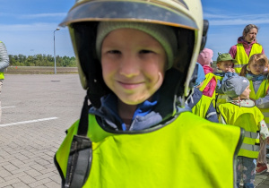 Dziecko przymierza kask strażacki.