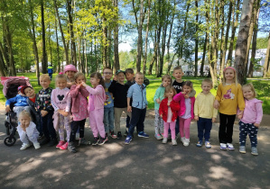Dzieci pozują do zdjęcia wśród drzew.