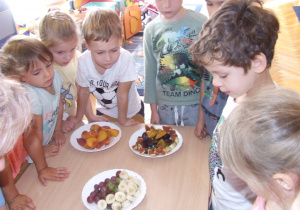 Dzieci oglądają pokrojone owoce.
