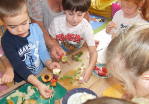 Dzieci robią szaszłyki owocowe.