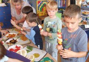 Dzieci robią szaszłyki owocowe.
