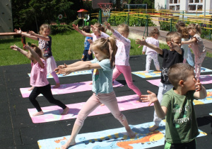 Dzieci wykonują pozycję wojownika.
