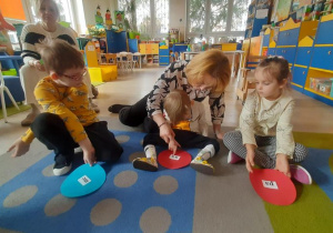 Chłopiec z pomocą nzuczycielki odvzytuje sylabę na swoim kółku.
