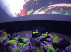 Dzieci leżą, oglądają hologram.
