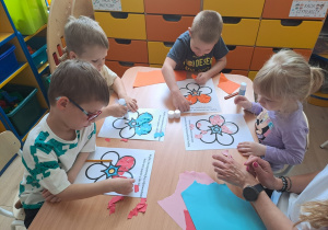 Dzieci wyklejają papierem kolorowym kwiat.
