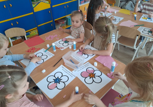 Dzieci wyklejają papierem kolorowym kwiat.