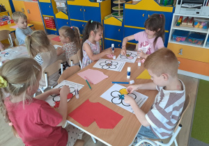 Dzieci wyklejają papierem kolorowym kwiat.