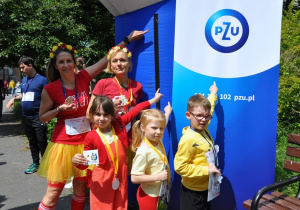 Dzieci z nauczycielkami pokazują baner sponsora.