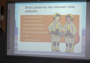 Dzieci oglądają prezentację o pracy strażaka.