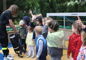 Dzieci podnoszą butlę z tlenem.