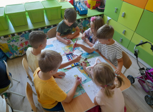 Dzieci malują farbami siedząc przy stoliku.