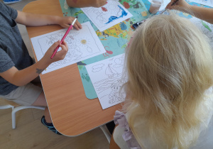 Dzieci malują farbami siedząc przy stoliku.