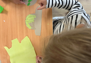Dziewczynka przykleja kawałki papieru kolorowego do szablonu auta.