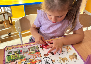 Dziewczynka koloruje kwiatek.