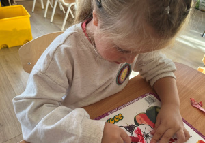 Dziewczynka koloruje kwiatek.