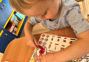 Chłopiec koloruje kwiatek.