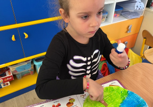 Dziewczynka przykleja pień drzewa na talerzu.