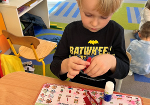 Chłopiec skleja pasek papieru.