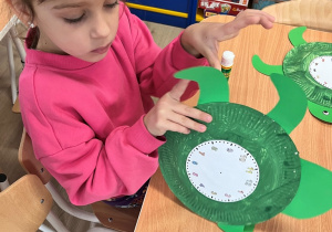 Dziecko nakleja elementy na talerzyk.