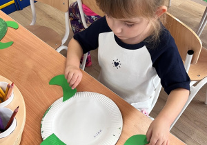 Dziecko nakleja elementy na talerzyk.