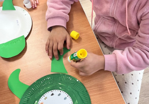 Dziecko nakleja elementy na talerzyk.