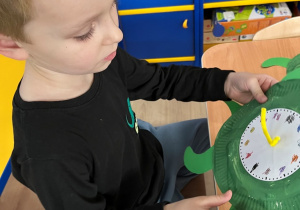 Dziecko nakleja elementy na talerzyk.