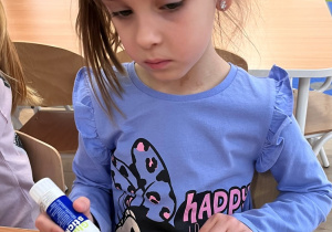 Dziecko smaruje klejem szablon skrzydeł ptaka.