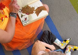 Nauczycielka pokazuje zasuszone liście w książce