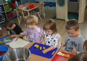 Dzieci kroją owoce.