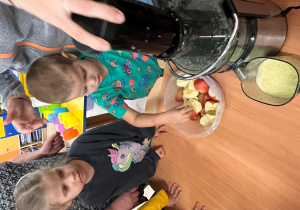 Chłopiec podaje jabłko do sokwirówki.