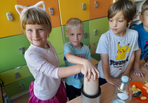 Dzieci miksują owoce w blenderze.