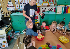Dzieci wrzucają owoce do sokowirówki.