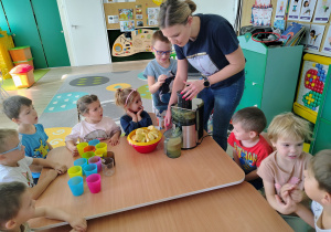 Dzieci wrzucają owoce do sokowirówki.