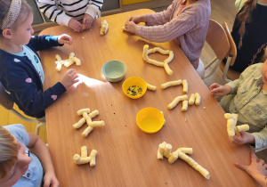Dzieci wykonują figurki z chrupek kukurydzianych.