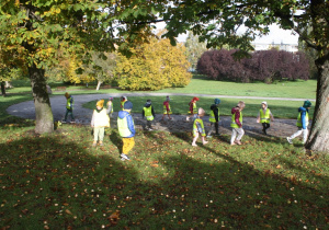 Dzieci szukają kasztanów w parku.