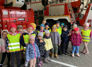 Dzieci pozują do zdjęcia na tle wozu strażackiego.