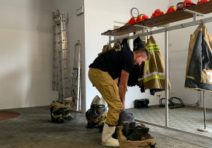 Strażak ubiera strój gaśniczy.