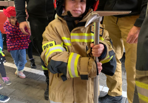 Dziecko pozuje do zdjęcia w stroju strażaka.