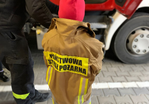Dziecko ubiera strój strażaka.