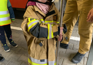 Dziecko pozuje do zdjęcia w stroju strażaka.