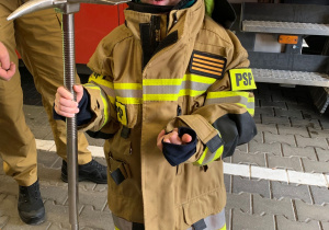 Dziecko pozuje do zdjęcia w stroju strażaka.