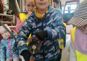 Dzieci pozują do zdjęcia z wężem strażackim.