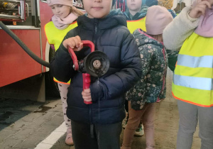 Dzieci pozują do zdjęcia z wężem strażackim.